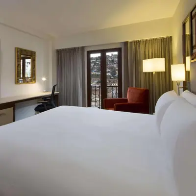 a hotel room with a large white bed and a chair at Hilton Garden Inn Cusco in Cusco