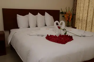 a bed with a bouquet of roses and a pair of shoes at Aqua Hotel Cusco in Cusco