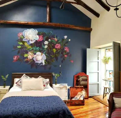 a bedroom with a painting of flowers on the wall at Niños Hotel Fierro in Cusco