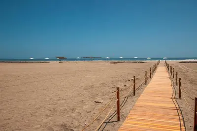 a wooden boardwalk stretches across the beach at DM Hoteles Asia in Asia