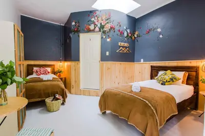 a bedroom with two beds and a blue wall at Niños Hotel Meloc in Cusco