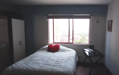 a bedroom with a bed with a red pillow on it at Cozy Room - Margot Arimborgo in Lima