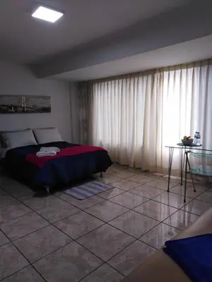 a bedroom with a bed and a table and curtains at Hospedaje de Lidia in Lima