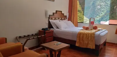 a bedroom with a bed with a table and a chair at Hostal Vista Waynapata 123 in Machu Picchu