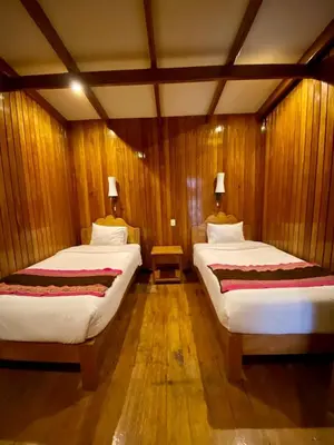 two beds in a room with wooden walls at Mistico Machupicchu Eco B&B in Machu Picchu