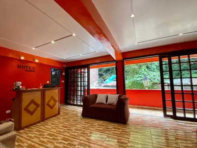 a living room with red walls and a couch andwindows at Mistico Machupicchu Eco B&B in Machu Picchu