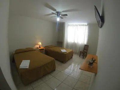 a room with two beds and a ceiling fan at Hospedaje el Telar in Nazca