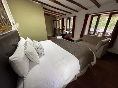 a bedroom with a large white bed and a couch at Parwa Guest House in Ollantaytambo