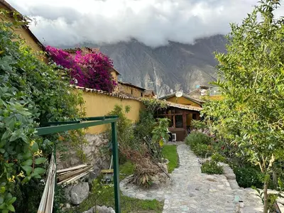 a house with a stone walkway in front of a mountain at Parwa Guest House in Ollantaytambo