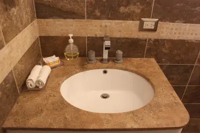 a bathroom sink with a bottle of wine and towels at Caihuayna Apart Hotel in Paracas
