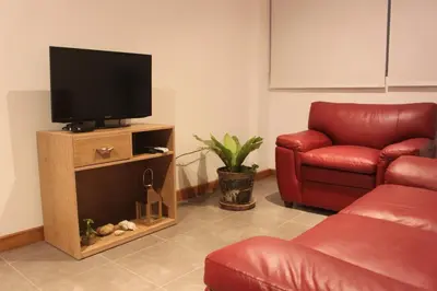a living room with a couch and a television at Caihuayna Apart Hotel in Paracas