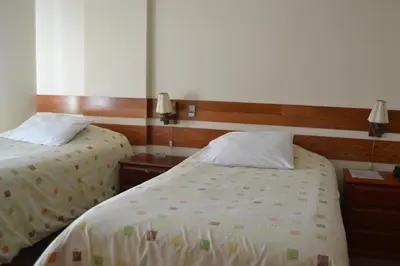 a hotel room with two beds and two night stands at Suite Service Apart Hotel in Lima