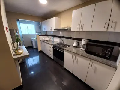a kitchen with white cabinets and a black appliance at MLA apartments - Kennedy in Lima