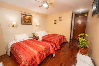 a hotel room with two beds and a ceiling fan at Hotel Manhattan Inn Airport in Lima