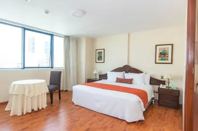 a hotel room with a large bed and a table at Miraflores Colon Hotel in Lima