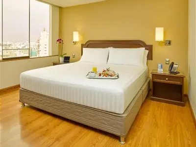 a bed in a hotel room with a tray of food on it at Hotel Estelar Miraflores in Lima
