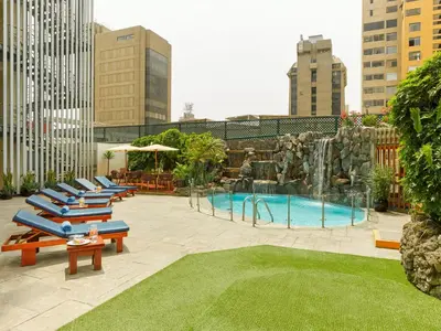 a group of lounge chairs and a pool with a fountain at Hotel Estelar Miraflores in Lima