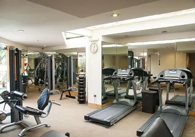 a gym with several tread machines and a mirror at Hotel Estelar Miraflores in Lima