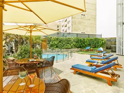 a patio with chairs and umbrellas and a pool at Hotel Estelar Miraflores in Lima
