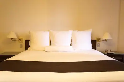 a large bed with white pillows and two lamps at J&A Classic Hotel in Lima