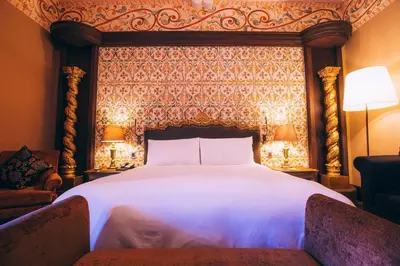 a bedroom with a large white bed and a wall at Palacio del Inka, a Luxury Collection Hotel, Cusco in Cusco