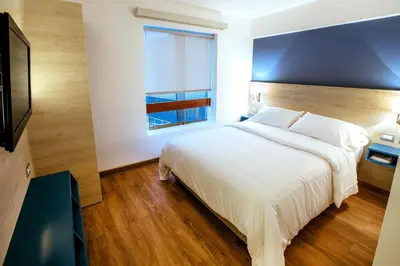 a bedroom with a large white bed and a window at Daniel's Apart Hotel in Lima