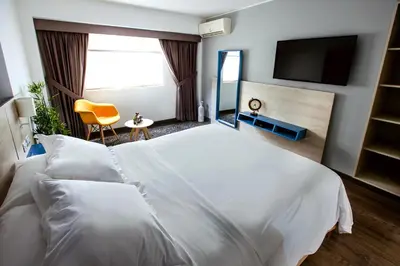 a bedroom with a white bed and a television at Daniel's Apart Hotel in Lima