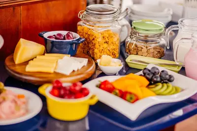 a table topped with cheese and vegetables and jars of food at Daniel's Apart Hotel in Lima