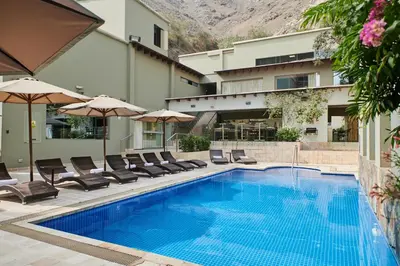a swimming pool with chairs and umbrellas next to a building at Casa Andina Premium Golf Los Incas in Lima