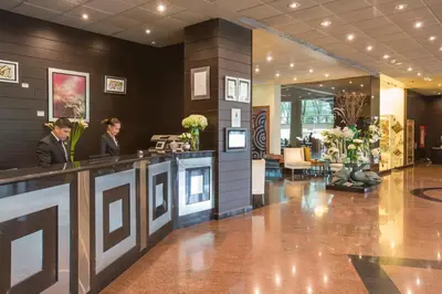 two people standing at a counter in a lobby at Delfines Hotel & Convention Center in Lima
