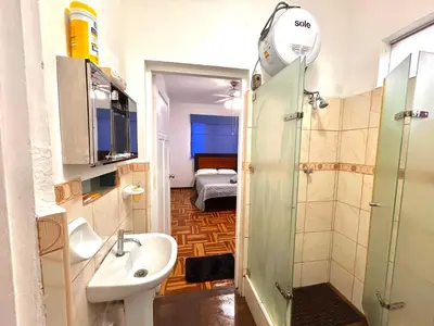 a bathroom with a sink and a shower and a bedroom at Departamento en San Isidro in Lima