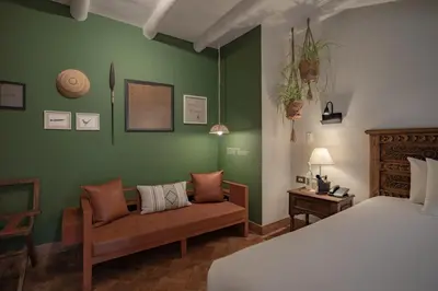 a bedroom with green walls and a bed and a couch at Antigua Casona San Blas in Cusco
