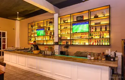 a bar in a restaurant with a man behind the counter at Hacienda San Juan Resort in Ica