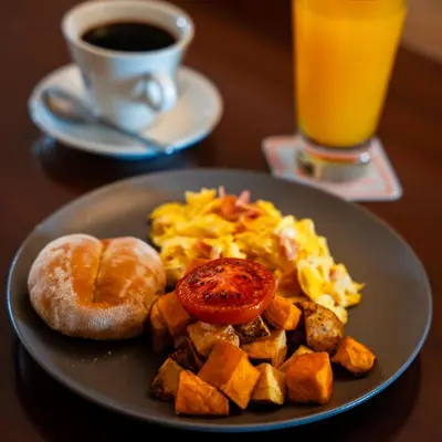 a plate of breakfast food with a donut and a cup of coffee at Hacienda San Juan Resort in Ica