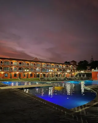 a building with a pool of water at night at Hacienda San Juan Resort in Ica