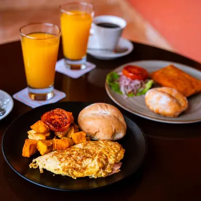 a table with two plates of breakfast foods and orange juice at Hacienda San Juan Resort in Ica