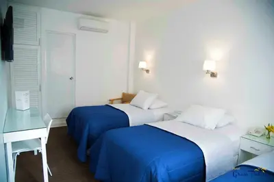 a hotel room with two beds and a desk at Hotel Gran Palma Huancayo in Huancayo