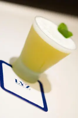 a cup of juice with a green leaf on it at Lyz Business Hotel in Lima