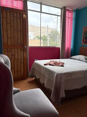 a bedroom with a bed and a window and a chair at La Casa de Bamboo in Ica