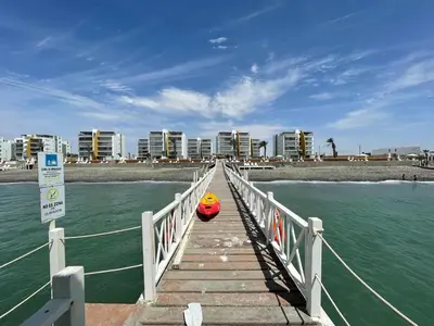 a dock with a red boat on the water at ooo OCEAN VIEW APARTMENT PARACAS SOTAVENTO ooo in Paracas
