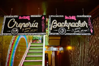 a pair of signs hanging from a building with a rainbow at Backpacker La Bo'M in Cusco
