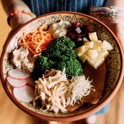 a bowl of food with broccoli and other vegetables at Backpacker La Bo'M in Cusco