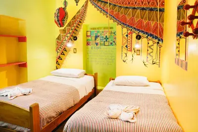 two beds in a room with yellow walls at Backpacker La Bo'M in Cusco