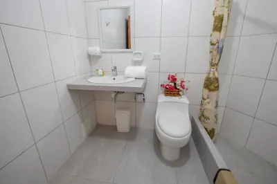 a white bathroom with a toilet and a sink at Amazonia Siu Hostal in La Merced