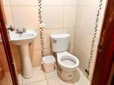 a small bathroom with a toilet and a sink at Hostal El Rancho in Huancayo