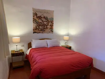 a bedroom with a red bed with two lamps at Hospedaje Killipata in Cusco
