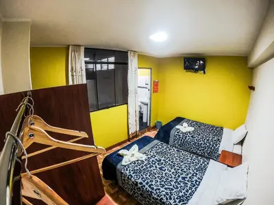 a room with two beds and a yellow wall at Hostal Berlin in Jauja