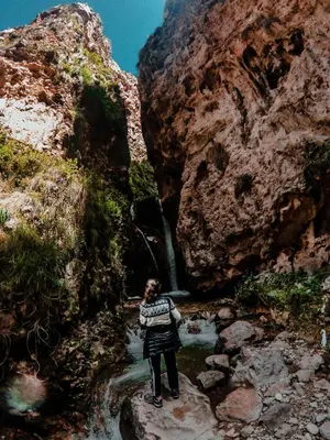 a woman standing in a stream in front of a waterfall at Hostal Berlin in Jauja