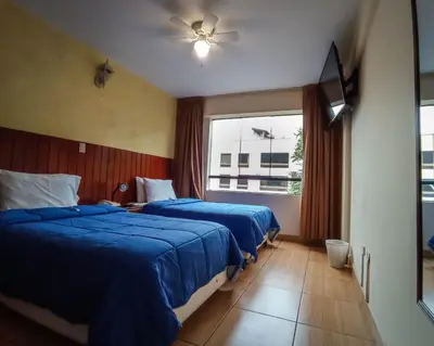 a hotel room with two beds and a window at Hotel El Farolito in Lima