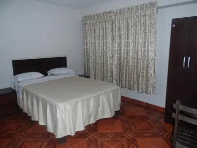 a bedroom with a bed and a window with curtains at Antares Inn in Lima